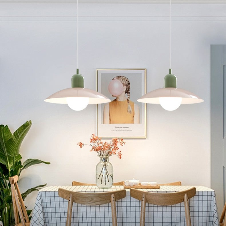 Två pendellampor med rosa skärmar och gröna toppar ovanför ett dukat matbord med stolar 5