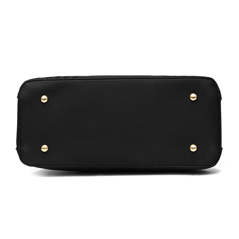 Schwarze Lederhandtasche Unterseite mit goldenen Nieten, elegante Damenmode Accessoire.
