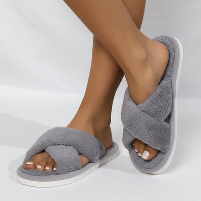 Grå fluffiga innesandaler med korsade remmar och vit sula på en modells fötter, ena foten lyft i sidled. 5