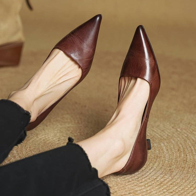 Bruna pumps med spetsig tå och låg klack på en modells fötter, på en halmmatta 21