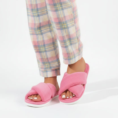 Rosa fluffiga innesandaler med korsade remmar buret av en modell i rutiga pyjamasbyxor i rosa, gult och blått. 2