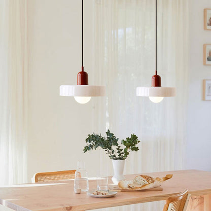 Zwei moderne Hängelampen, rot-weiß, über Esstisch mit Brot und Vase, skandinavisches Design.