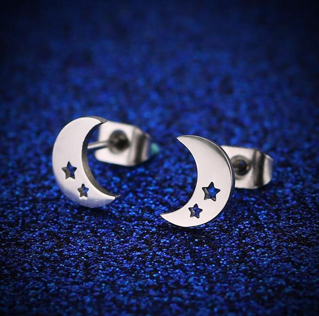 Silberne Edelstahl-Ohrringe mit Mond- und Sternmotiv auf blauem Hintergrund.