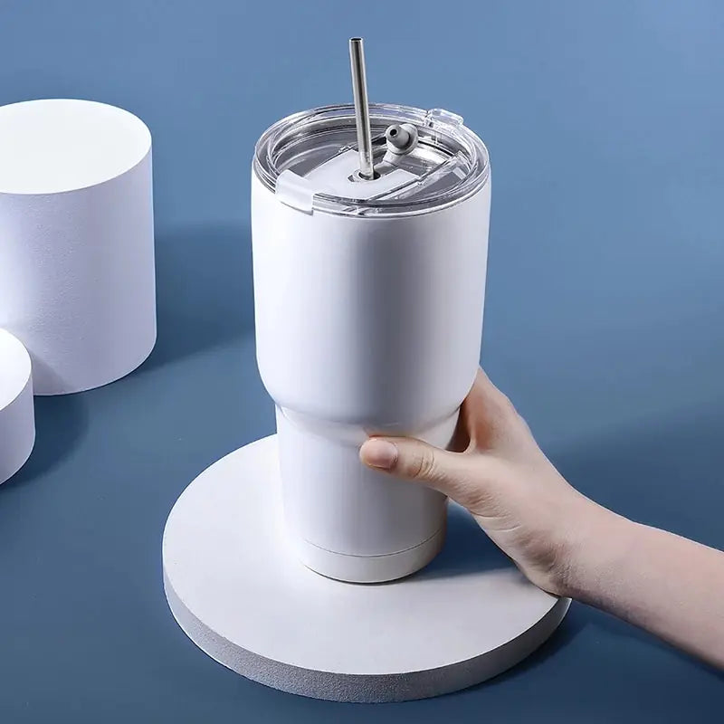 Weißer Thermobecher mit Strohhalm, Edelstahl, isoliert, Hand hält Becher, blauer Hintergrund