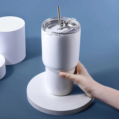 Weißer Thermobecher mit Strohhalm, Edelstahl, isoliert, Hand hält Becher, blauer Hintergrund