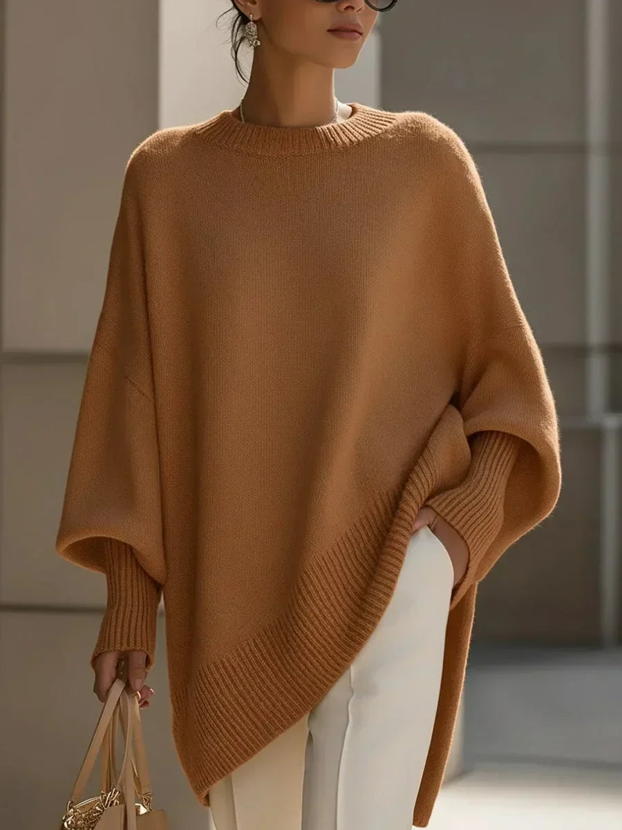 Modell bär den kamelbruna versionen av tröjan med ribbade ärmslut och vita byxor, helfigur framifrån. 12