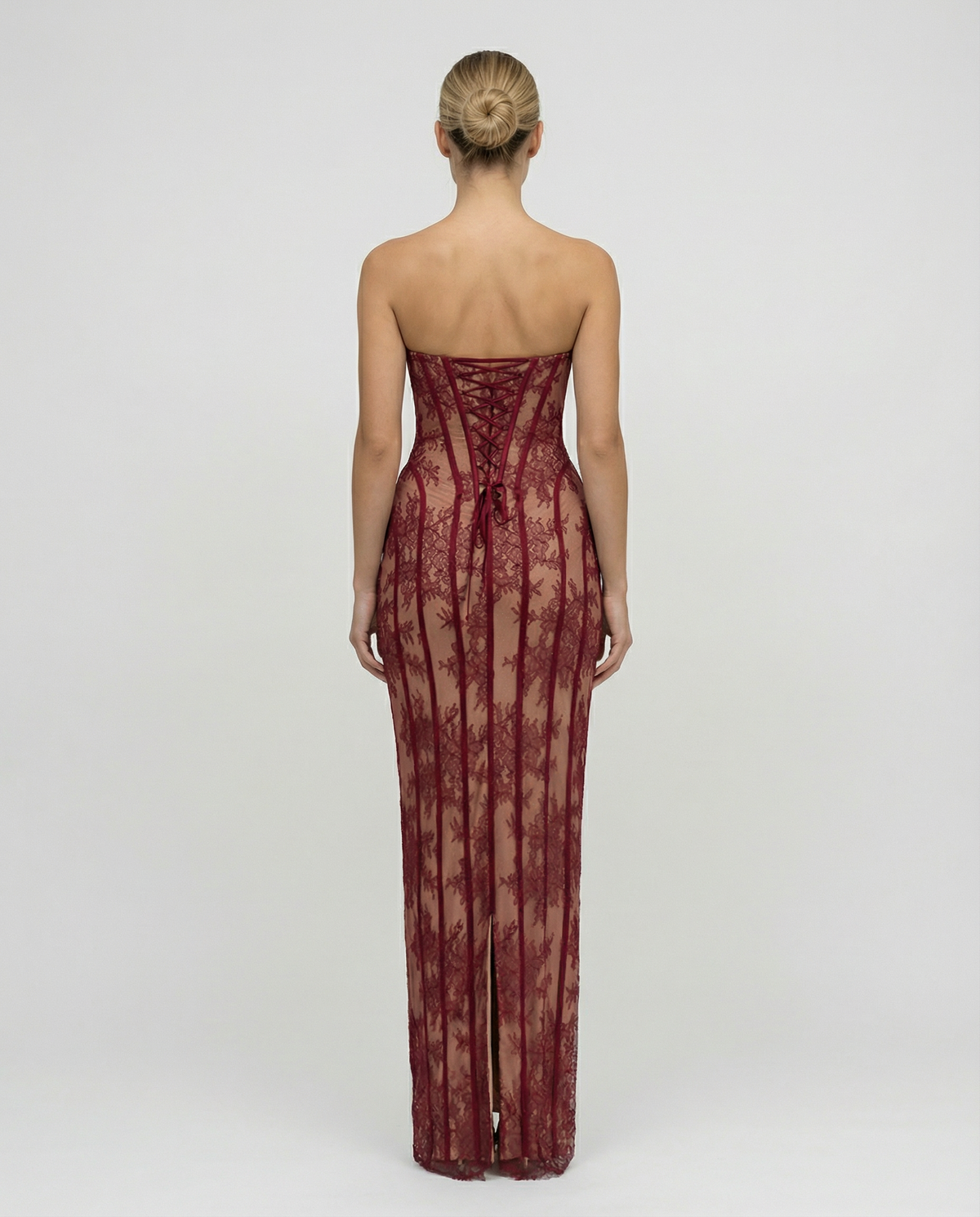 Klänningen bakifrån i vinröd spets, med snörning i ryggen och en slits längst ned i bakstycket. 2