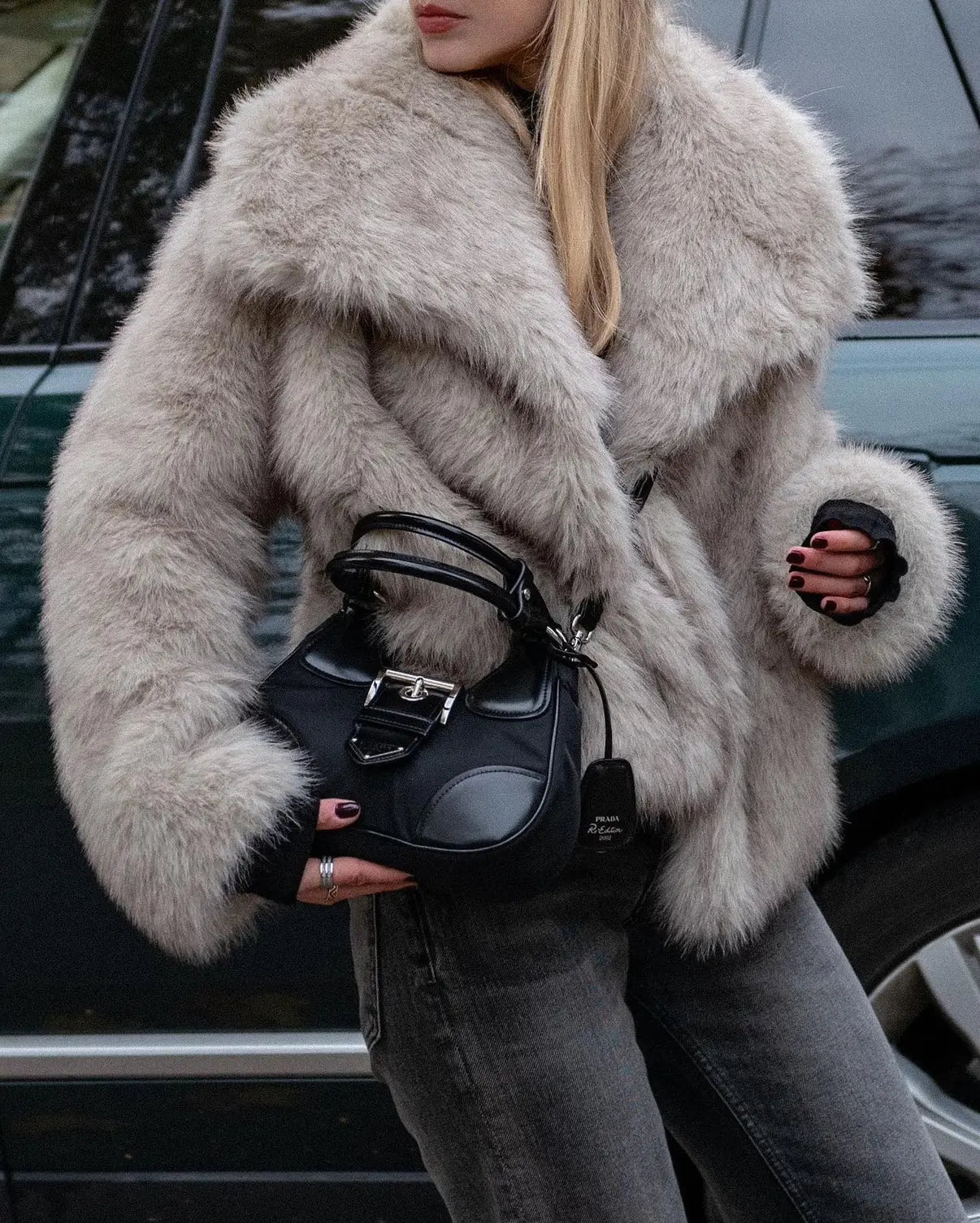 Frau in grauem Pelzmantel hält schwarze Designer-Handtasche, Mode, Winterkleidung.