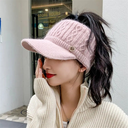 Frau mit rosa Strick-Visor-Mütze, Zopfmuster, modisch, Herbstmode, draußen.