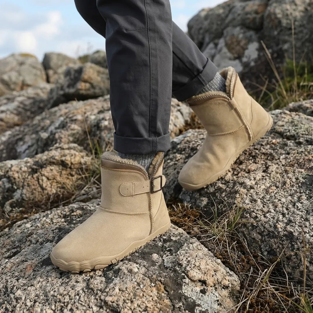 Beige kängor i mocka på fötter som kliver upp på klippor, med grå byxor 2
