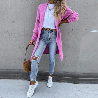Frau in rosa Strickjacke, weiße Sneakers, zerrissene Jeans, braune Tasche, lässiger Stil.
