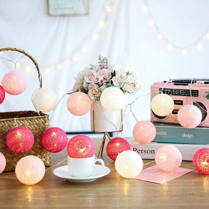 Rosa und weiße Lichterkette, dekorative Kugeln, Tischdekoration, gemütliche Beleuchtung.