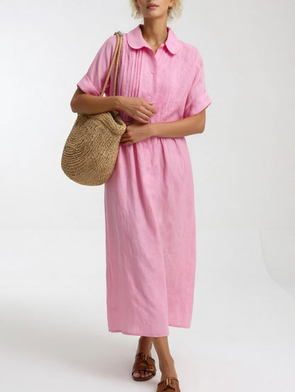 Klänningen i rosa på modell som bär en flätad väska på axeln, med uppvikta korta ärmar och knappslå framtill. 4