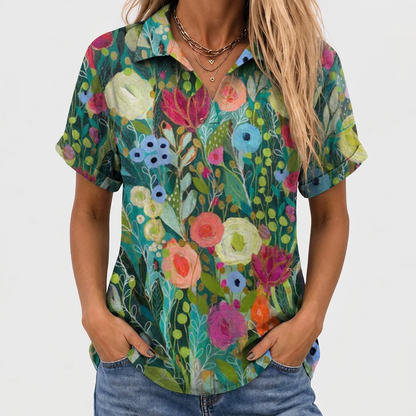 Närbild framifrån på modell med händerna i jeansfickorna, toppens färgglada blommönster och uppvikta korta ärmar syns 1