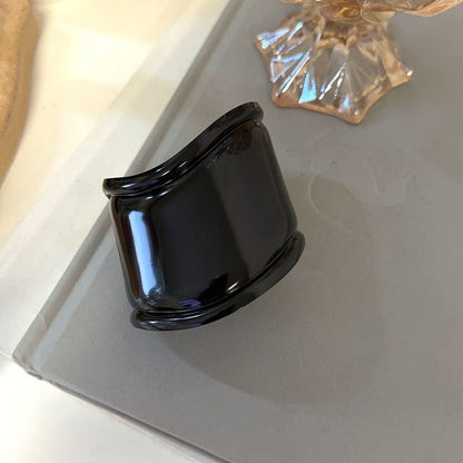 Schwarzes, breites Metallarmband mit asymmetrischen Wellenöffnungen, modisches Accessoire.