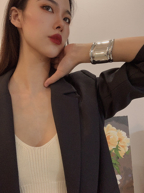 Frau mit silbernem, breitem Metallarmreif, modisch, asymmetrisches Design, eleganter Look.