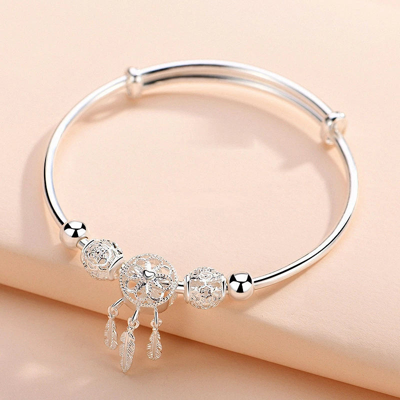 Silbernes Damenarmband mit Federn und Kreuzanhänger, elegantes Schmuckdesign.
