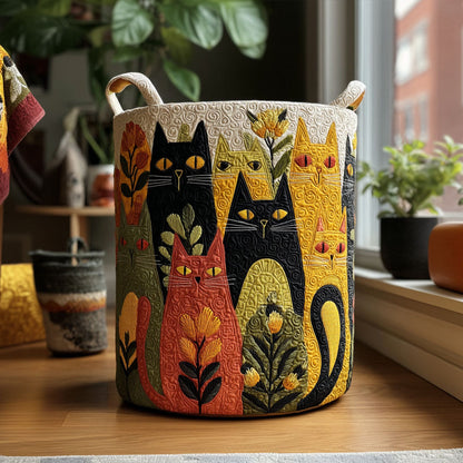 Rund vadderad korg med quiltade, färgglada katter och blommor och två handtag, stående på ett trägolv vid ett fönster. 1