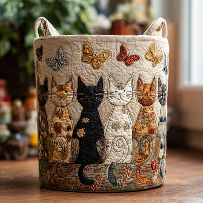 Rund vadderad korg med två handtag, applikerade fjärilar och en rad sittande katter i lapptekniksstil, stående på ett träbord. 1