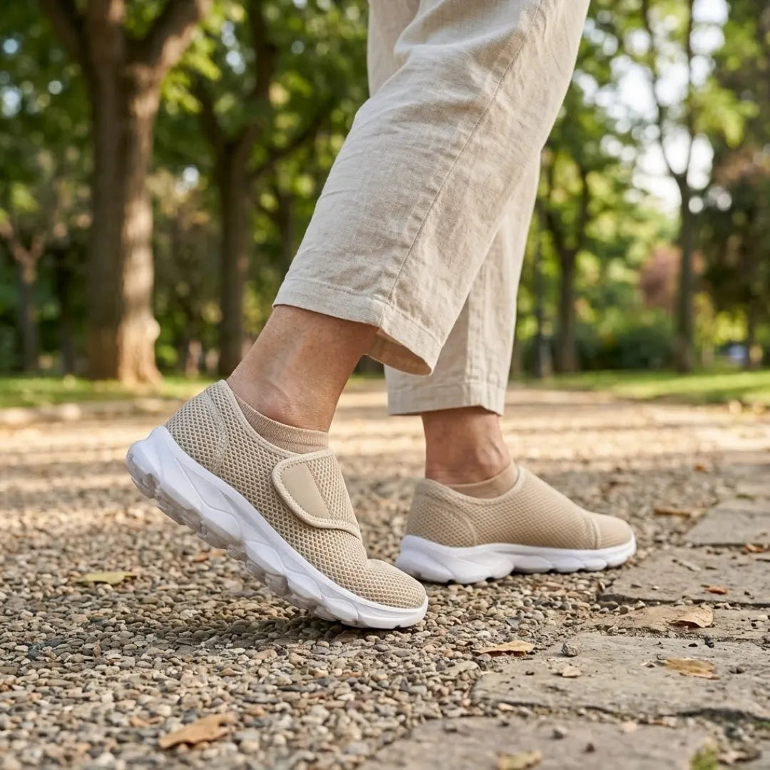 Person i beige linnebyxor går på grusväg i en park, bärande beige mesh-skor med kardborreband och vit sula. 29