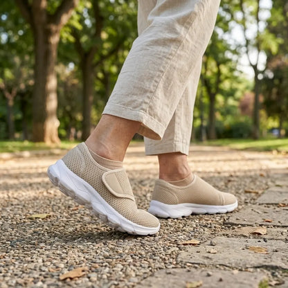 Person i beige linnebyxor går på grusväg i en park, bärande beige mesh-skor med kardborreband och vit sula. 29