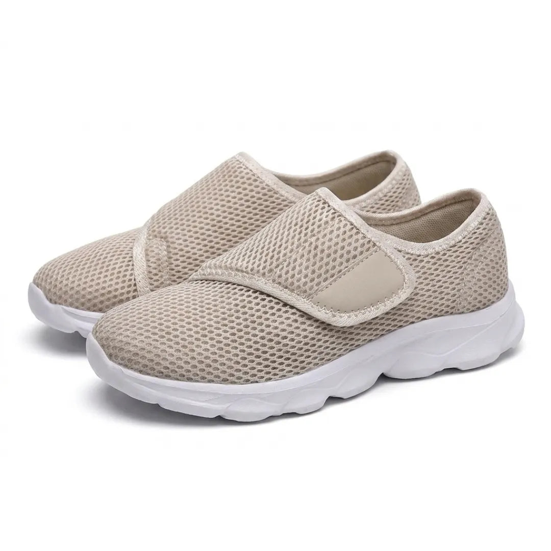 Ett par beige mesh-skor med justerbart kardborreband och vit sula, sedda snett framifrån på vit bakgrund. 34