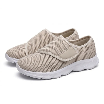 Ett par beige mesh-skor med justerbart kardborreband och vit sula, sedda snett framifrån på vit bakgrund. 34