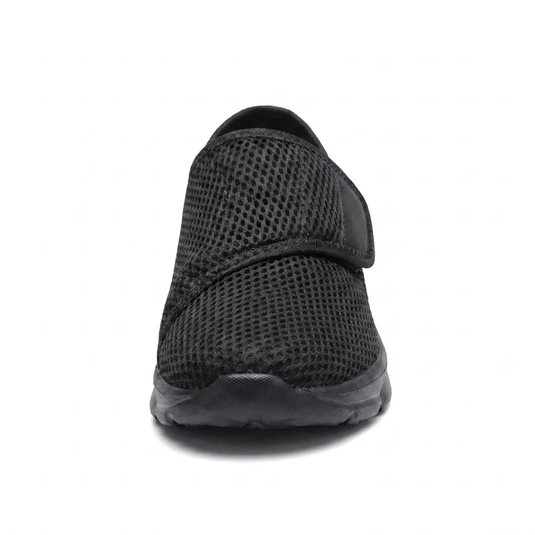 Svart mesh-sko rakt framifrån med kardborrebandet över vristen och bred, rundad tå. 17