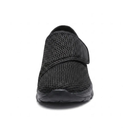 Svart mesh-sko rakt framifrån med kardborrebandet över vristen och bred, rundad tå. 17