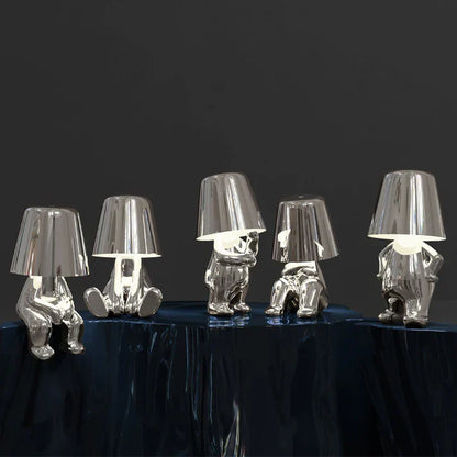 Fünf silberne Tischlampen in menschlicher Form auf dunklem Hintergrund, modernes Design.