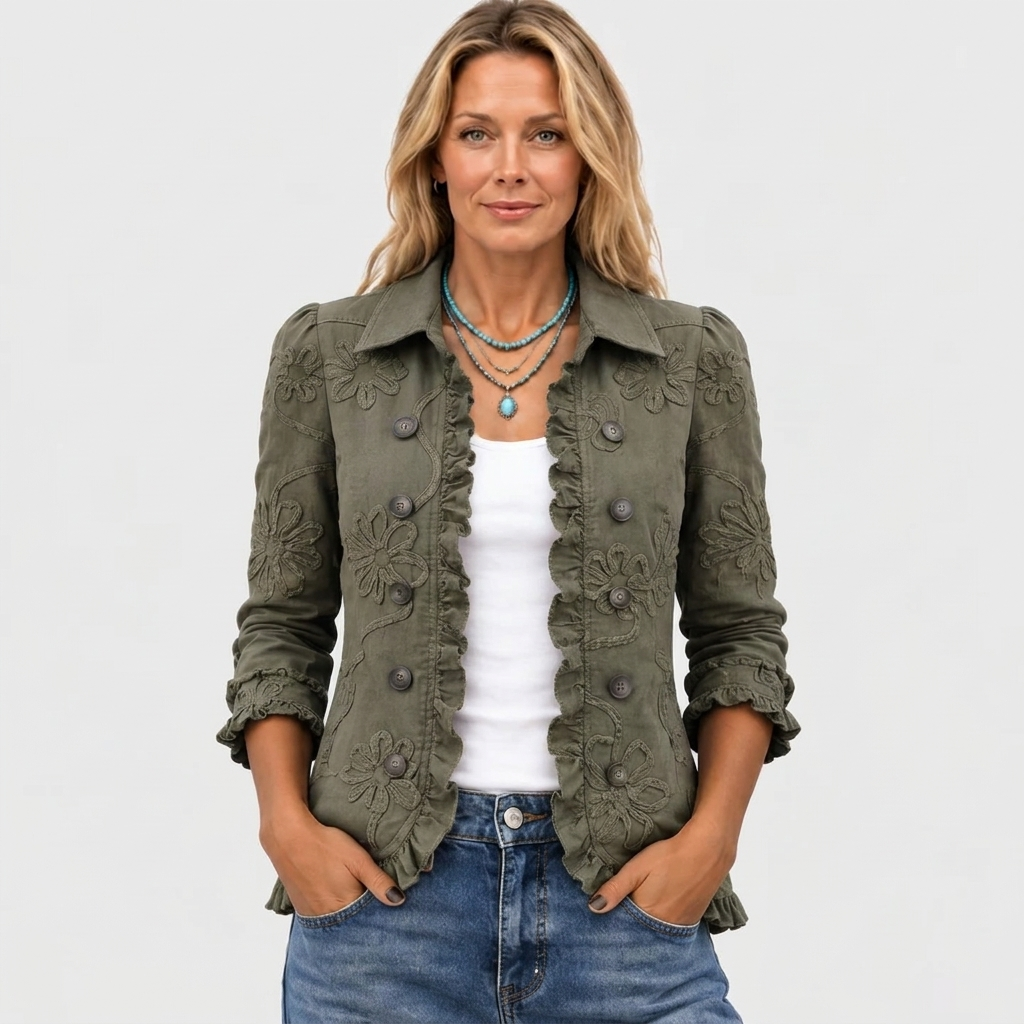 Modell framifrån i den olivgröna jackan med broderade blommor och volanger, bär den öppen över vitt linne, jeans och turkost halsband. 2