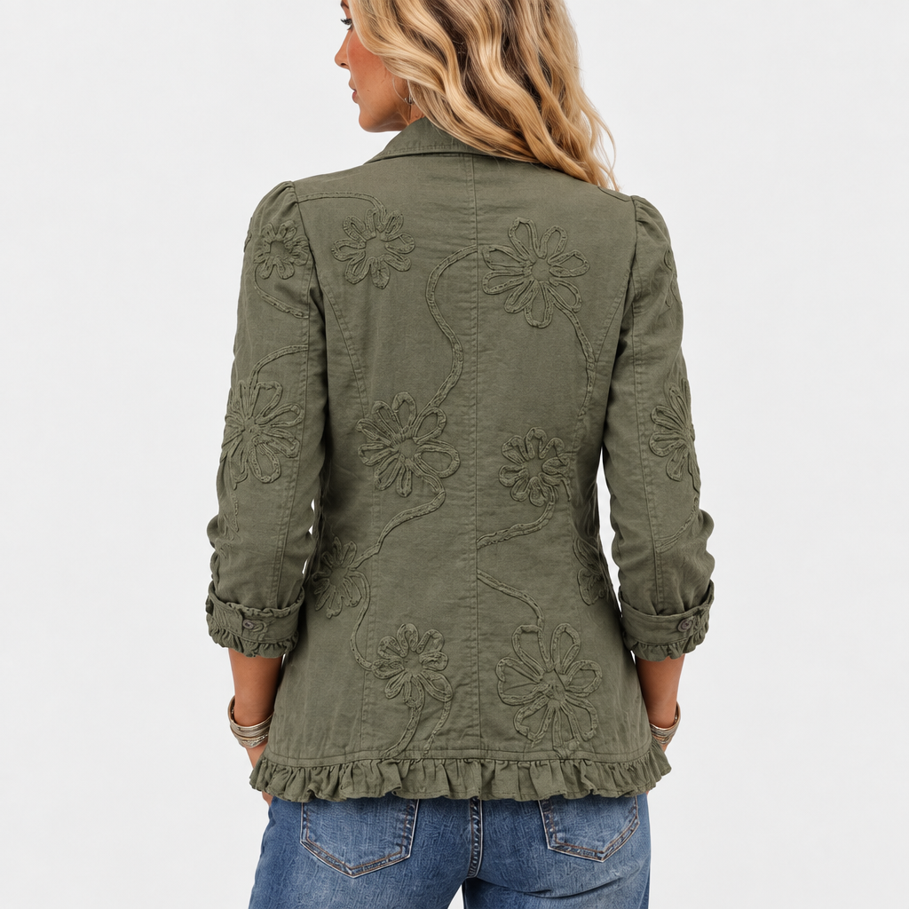 Jackans rygg på modellen, med stora broderade blommor och rankor samt volangkant nedtill och vikta, volangprydda ärmslut. 5
