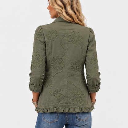 Jackans rygg på modellen, med stora broderade blommor och rankor samt volangkant nedtill och vikta, volangprydda ärmslut. 5