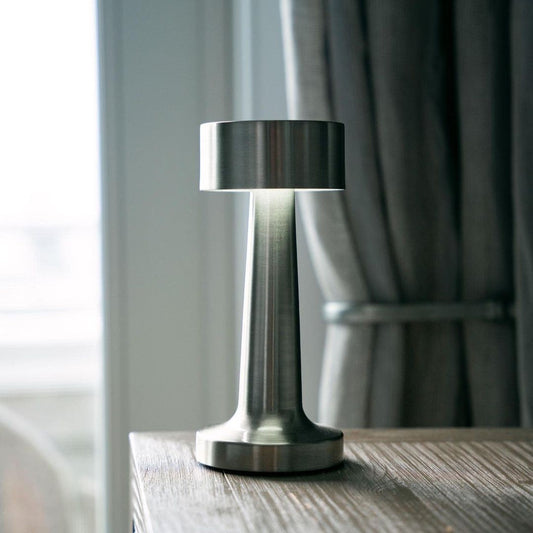 Moderne silberne Tischlampe aus Metall auf Holztisch, ideal für Restaurant oder Barbeleuchtung.