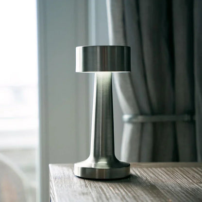 Moderne silberne Tischlampe aus Metall auf Holztisch im Restaurant, stilvolle Beleuchtung.