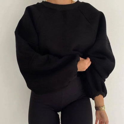 Frau trägt schwarzes Oversize-Sweatshirt, moderne Damenmode, bequeme Freizeitkleidung.