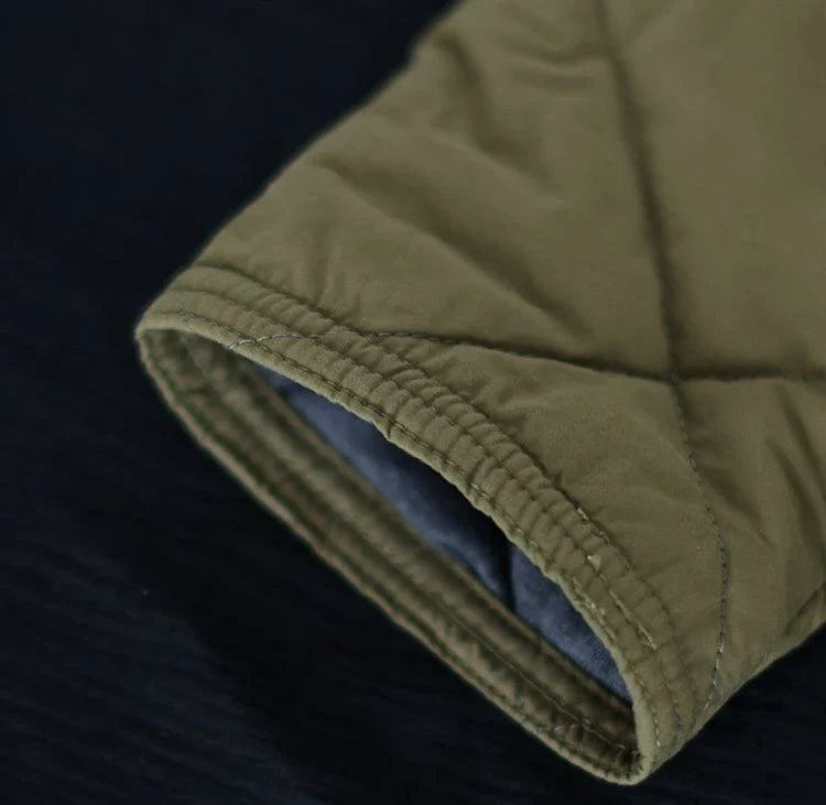 Olivgrüner, gesteppter Ärmel einer Winterjacke aus Baumwolle auf dunklem Hintergrund.