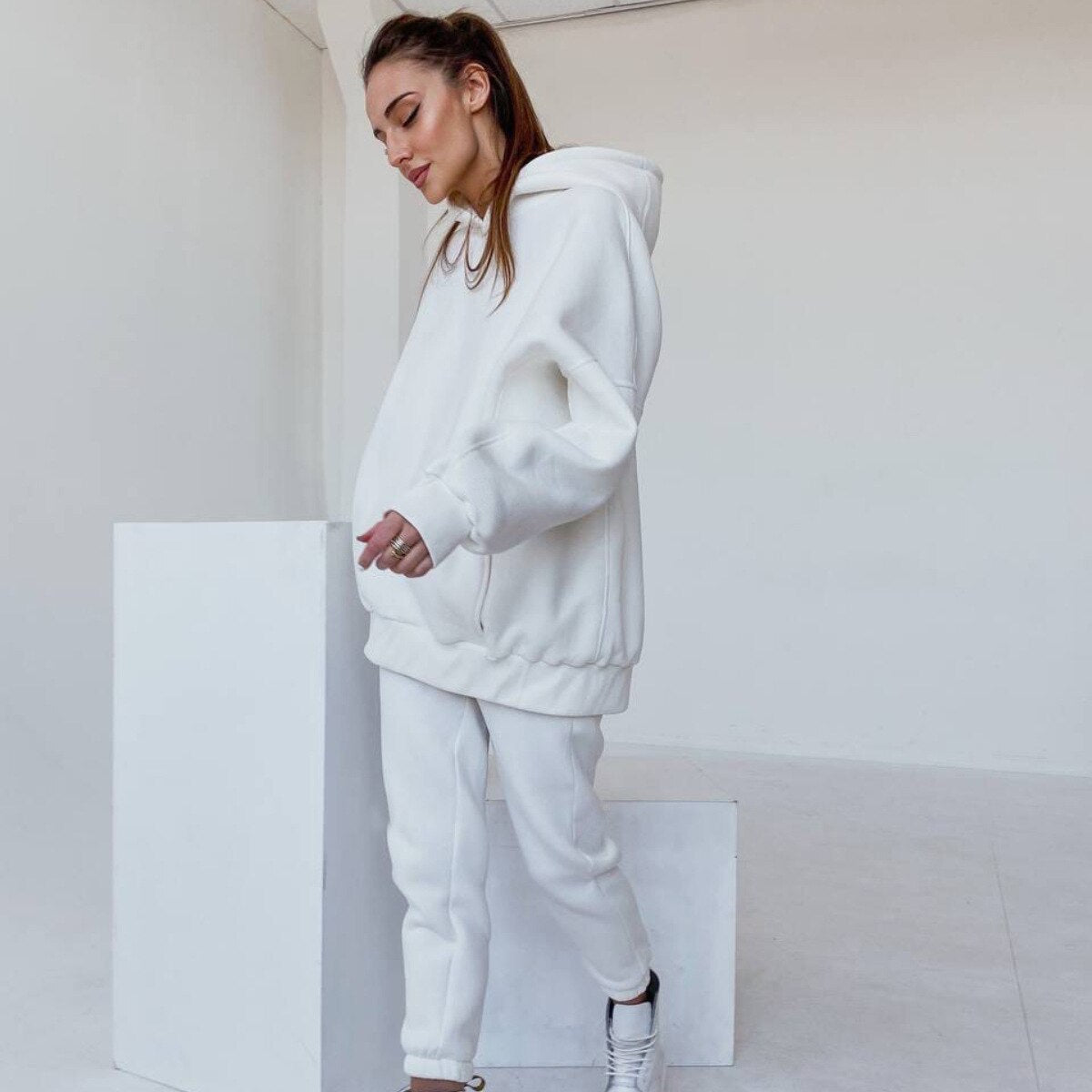 Frau in weißem Hoodie und Jogginghose, lässige Mode, bequeme Freizeitkleidung, minimalistisch.