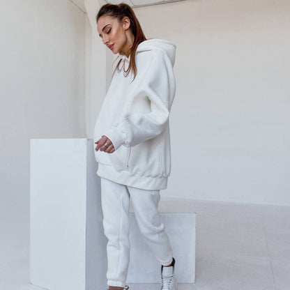 Frau in weißem Hoodie und Jogginghose, lässige Mode, bequeme Freizeitkleidung, minimalistisch.