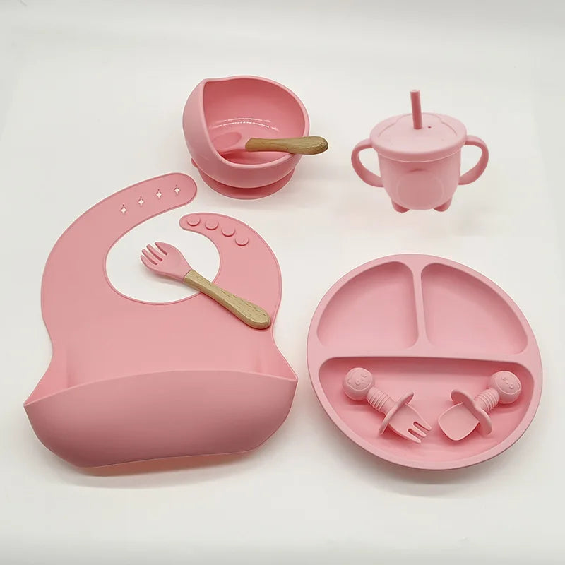 Rosa Silikon-Babyteller-Set mit Lätzchen, Becher, Schüssel und Besteck für Kleinkinder.