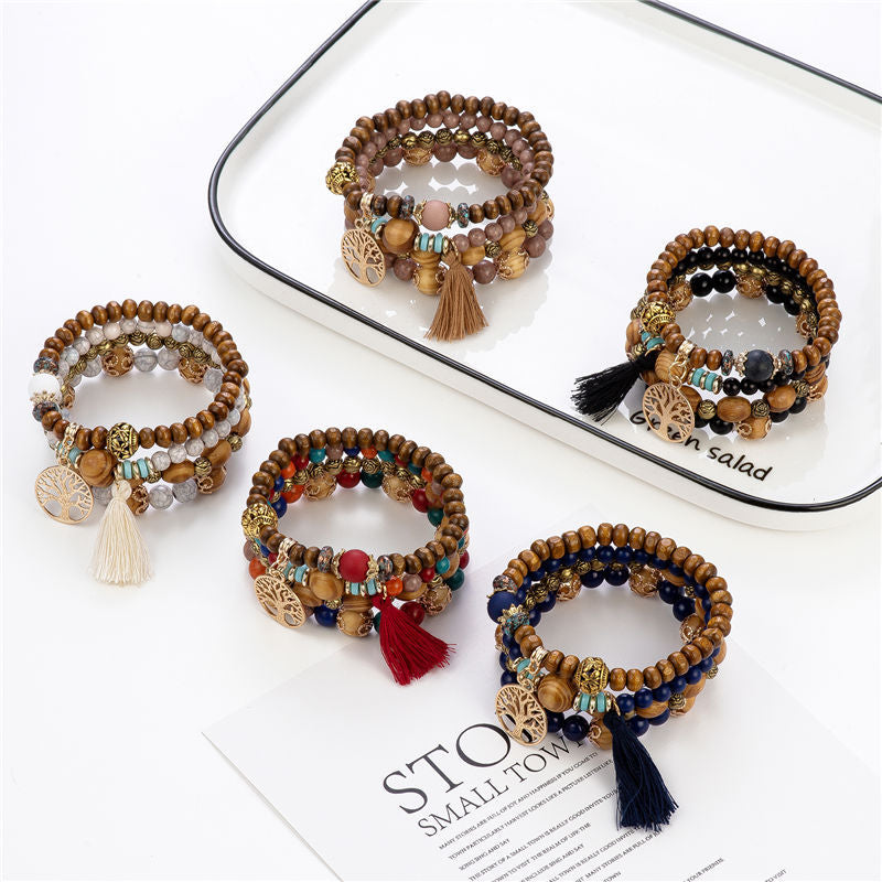 Fünf Holzarmbänder mit Quasten und Perlen auf weißem Hintergrund, Boho-Stil, handgefertigt.