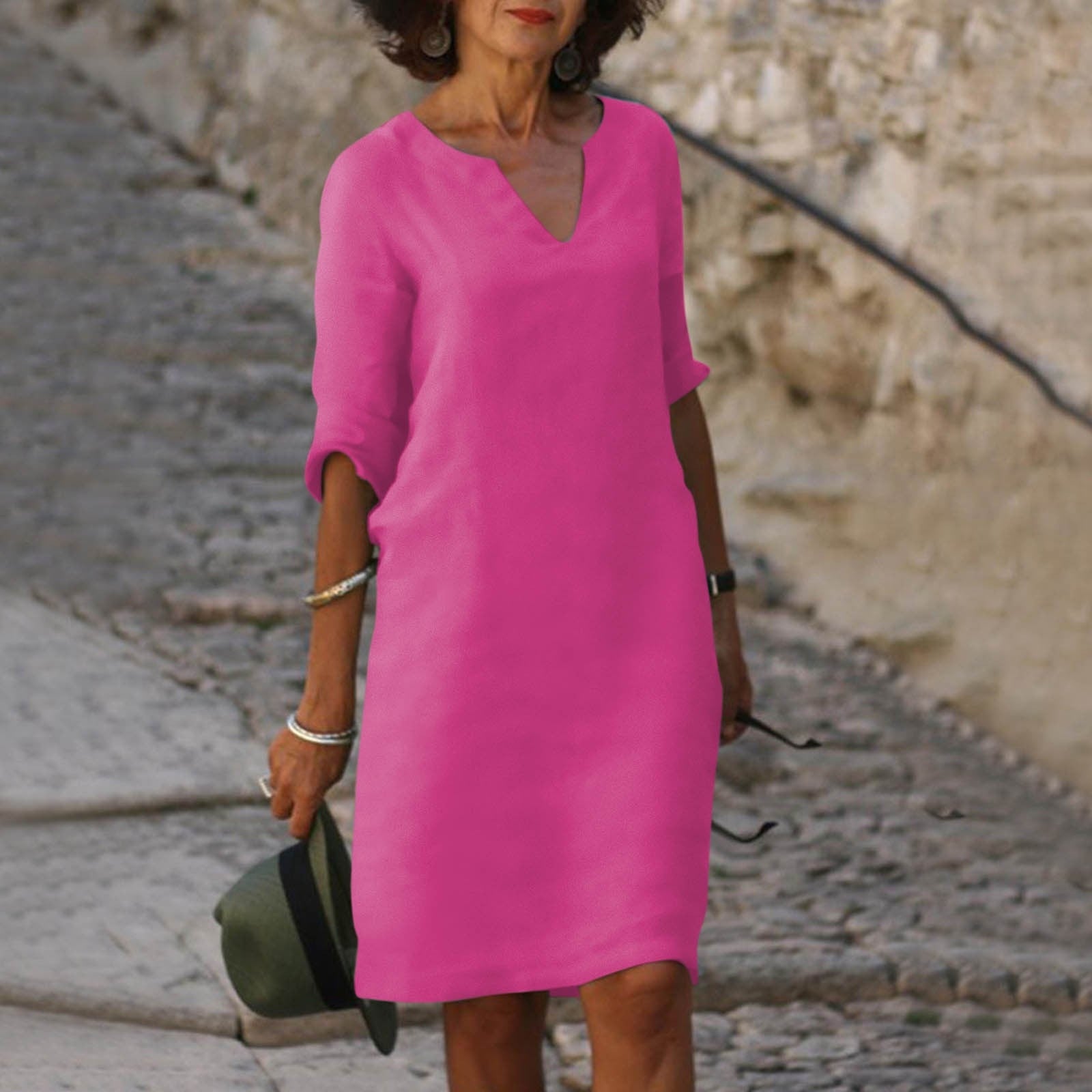 Frau in pinkem Sommerkleid auf Kopfsteinpflasterweg, modisch, elegant, Freizeitkleidung.