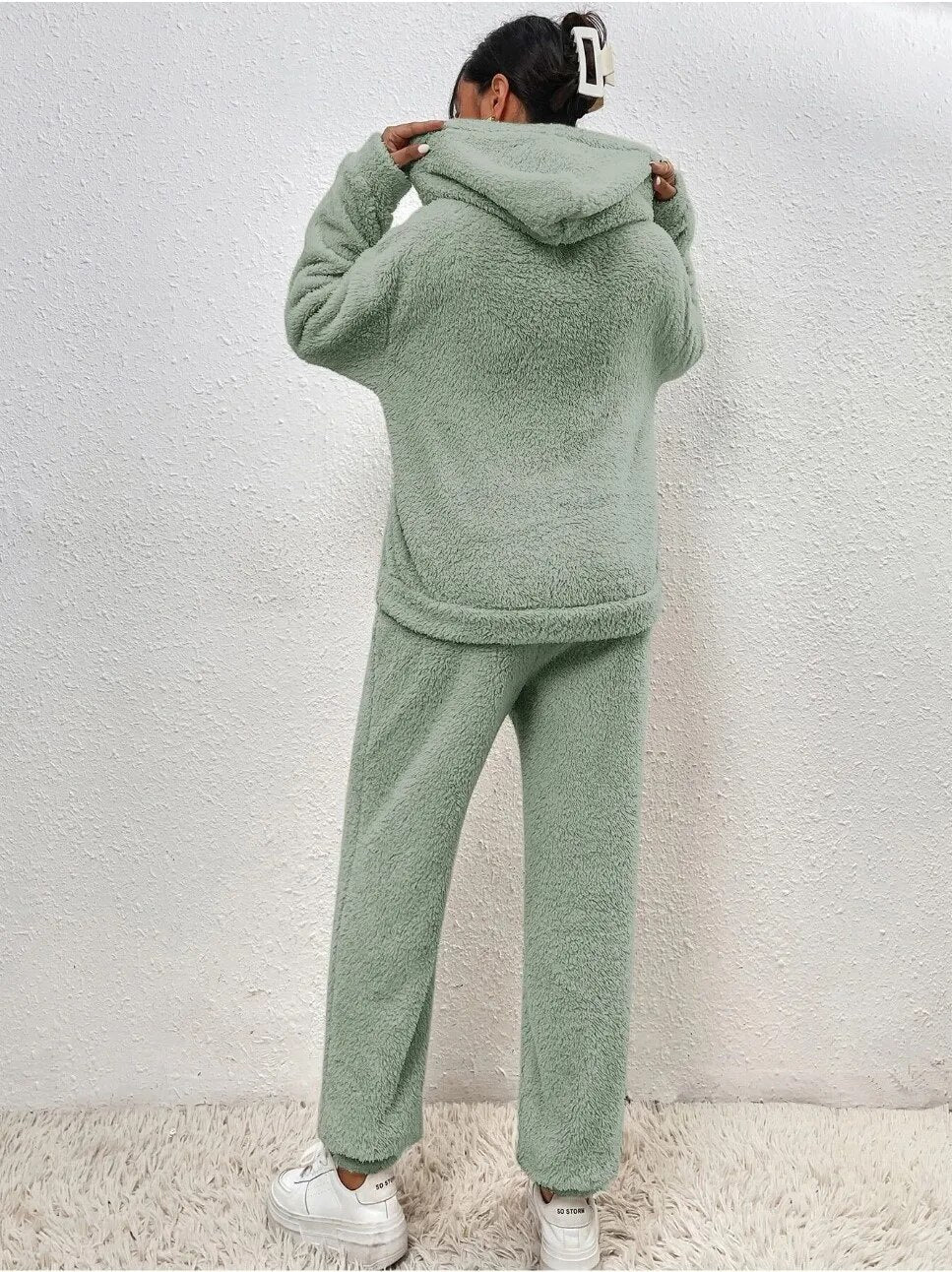 Frau in grünem Fleece-Set, Kapuzenpullover und Jogginghose, gemütliche Wintermode.