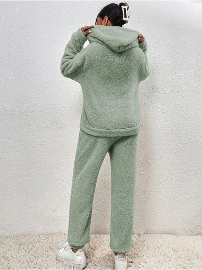 Frau in grünem Fleece-Set, Kapuzenpullover und Jogginghose, gemütliche Wintermode.