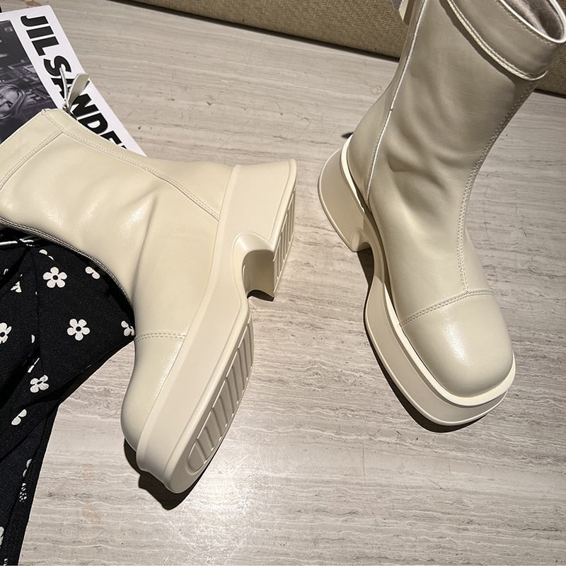 Weiße Lederstiefel mit Plateauabsatz auf Holzboden, modisch und elegant.