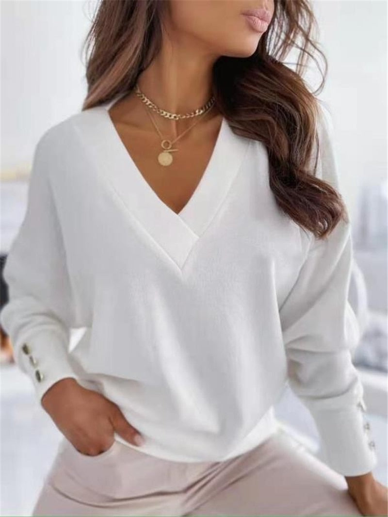 Frau in weißem V-Ausschnitt-Pullover mit Kettenhalskette, modisch, elegant, Freizeitkleidung.