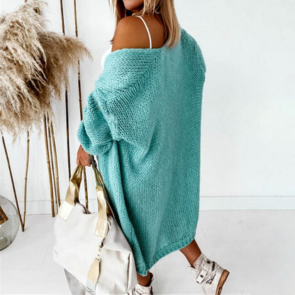Frau in türkisfarbenem Strickcardigan mit weißer Tasche, modisch, lässig, Herbstmode.