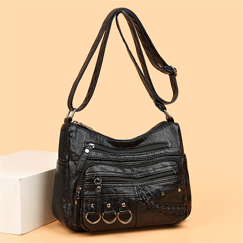 Schwarze Lederhandtasche mit Reißverschlüssen und Ringen, modisch und vielseitig.