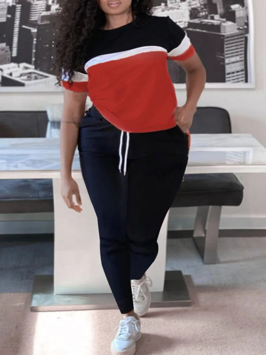 Frau in rotem und schwarzem Freizeitanzug, weiße Sneaker, modernes Wohnzimmer.