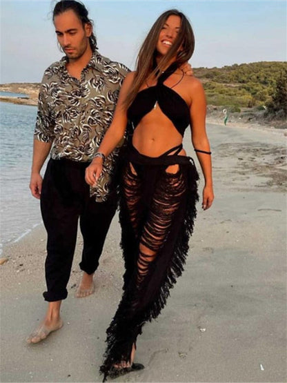 Paar am Strand, Frau in schwarzem, zerrissenem Strandkleid, Mann in gemustertem Hemd.